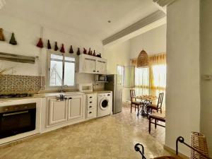 une cuisine avec des armoires blanches et une table avec des chaises dans l'établissement Sidi Bou Said for two, à Dar el Ouzir 16 autres photos