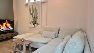 ein Wohnzimmer mit einem weißen Sofa und einem Fernseher in der Unterkunft Tip! Noordwijk city center house in Noordwijk aan Zee