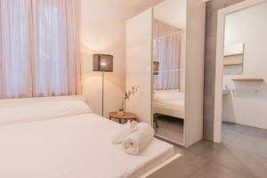 a white bedroom with a bed and a mirror at City Center - TinyStudio Piazza San Giacomo in Udine +5 photos