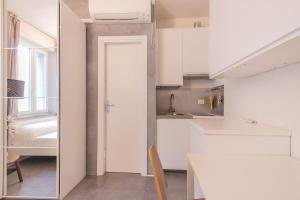 a kitchen with white cabinets and a table in a room at City Center - TinyStudio Piazza San Giacomo in Udine