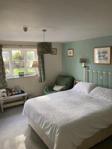 ein Schlafzimmer mit einem Bett und einem Stuhl und Fenstern in der Unterkunft Brandreth Barn in Burscough