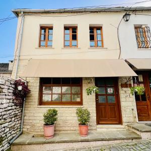 Una casa con toldo y plantas en macetas delante de ella. en Our Townhouse, en Gjirokastra