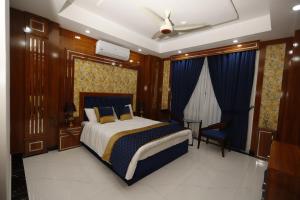 a bedroom with a bed and a chair in it at Qinwan Hotel & Suites in Rawalpindi