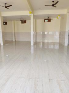 Uma sala grande e vazia com dois ventiladores de teto. em Hotel Pyaremohan em Vrindāvan