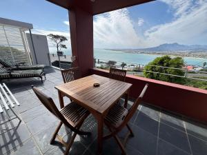 a wooden table and chairs on a balcony with a view at 5 Suikerbossie in Gordonʼs Bay