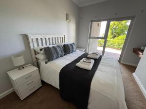 a bedroom with a large white bed with a window at 5 Suikerbossie in Gordonʼs Bay