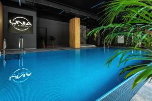 a swimming pool with blue water in a building at Prestige Luxury Spa Suite- Basen, Jacuzzi, Sauna & Prywatne Miejsce Parkingowe in Lublin