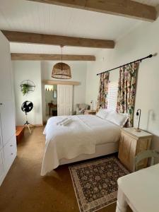 a bedroom with a large white bed and a desk at Jonkershuis Farm Retreat in Heidelberg