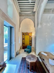 a room with a bed and a blue chair and a table at Suite tolila te house of medina of tunis in Tunis