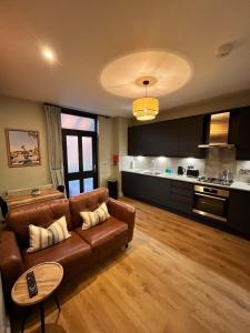 a living room with a brown couch and a kitchen at Beach Retreat, Stylish 1-Bed in Canford Cliffs in Canford Cliffs