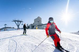 dos personas están esquiando por una pista cubierta de nieve en Thermenwelt Hotel Pulverer, en Bad Kleinkirchheim