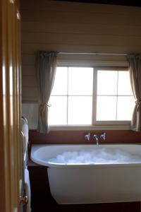 a bath tub in a bathroom with a window at 1860 Luxury Accommodation in Beechworth