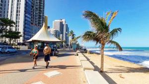 a man and a woman walking on the beach at Quarto Individual e Privativo - Apt moderno compartilhado com o Hoster - Boa Viagem in Recife
