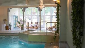 een zwembad met mensen die op stoelen in een huis zitten bij Lundsbrunn Resort & Spa in Lundsbrunn