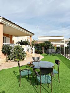 un patio con mesa y sillas en el césped en Villa en la Playa I 5BR I 5 WC I Piscina Privada, en Sueca