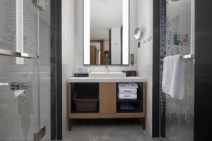 a bathroom with a sink and a mirror and a shower at Hampton by Hilton Cixi Guanhaiwei in Ningbo +27 photos