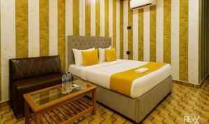 ラクナウにあるFabHotel Balajiのベッドと椅子とテーブルのある寝室