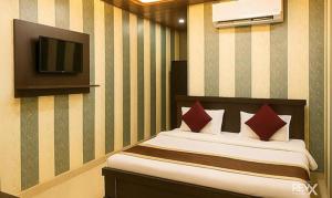 ラクナウにあるFabHotel Balajiのベッドと壁掛けテレビのある寝室