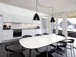a kitchen with a white table and black chairs at Exclusive Golf View Retreat in Rømø Kirkeby