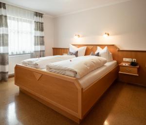 a bedroom with a large wooden bed with white pillows at App.-Haus zur Europa-Therme in Bad Füssing