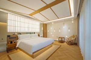 une chambre avec un grand lit blanc et une grande fenêtre dans l'établissement Huazhu Luxury Niushou Yinlan Homestay, à Sanbanqiao