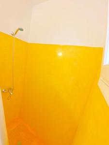 La salle de bains est pourvue d'un mur jaune et d'une douche. dans l'établissement Deluxe Apartment - Vlichada Beach, à Santorini 5 autres photos