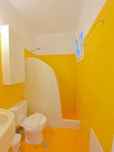 une salle de bain avec des toilettes blanches et des murs jaunes dans l'établissement Deluxe Apartment - Vlichada Beach, à Santorini