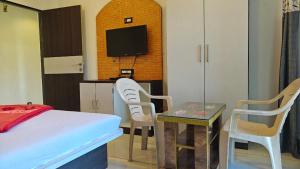 a room with a bed and two chairs and a tv at Hotel Prathamesh in Panchgani