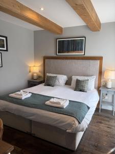 una habitación con una cama grande con sábanas y almohadas blancas en The Walhampton Arms, en Lymington