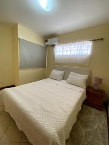 Un dormitorio con una gran cama blanca con ventana. en Cozy Studio in Grand Bay, en Grand Baie