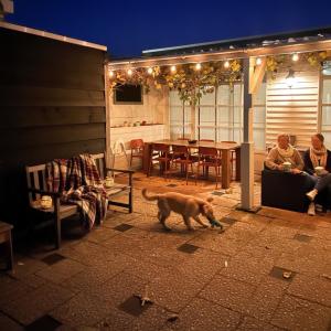 a dog walking on a patio with two people and a table at Family Retreat Zoutelande Beach in Zoutelande
