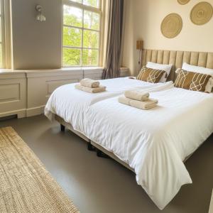 a bedroom with a large white bed with towels on it at Family Retreat Zoutelande Beach in Zoutelande
