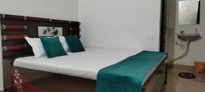 a bed with green and white pillows in a room at Hotel Holiday in Bharatpur +6 photos