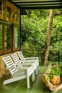 2 weiße Stühle und ein Tisch auf einer Veranda in der Unterkunft Wild Monkey Jungle Villa - 4 Bedroom Villa in Unawatuna