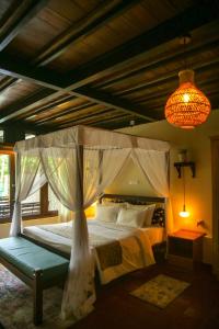 ein Schlafzimmer mit einem Himmelbett und einem Kronleuchter in der Unterkunft Wild Monkey Jungle Villa - 4 Bedroom Villa in Unawatuna