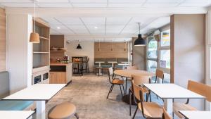 a restaurant with tables and chairs and a kitchen at Premiere Classe Bourges in Bourges
