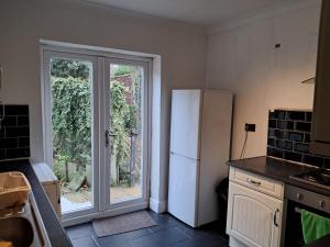 a kitchen with a refrigerator and a sliding glass door at Cosy 2 Bedroom Luxury House in Wednesbury