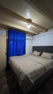a bedroom with a large bed with blue curtains at Dibi Krui Surf in Krui +8 photos