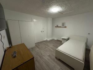 Schlafzimmer mit einem weißen Bett und einem Holztisch in der Unterkunft Exclusive Monteursunterkunft in Wunsiedel