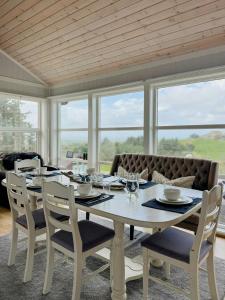 ein Esszimmer mit Tisch und Stühlen und Fenstern in der Unterkunft Coastal Cabin With Panoramic Views In Lista in Borhaug