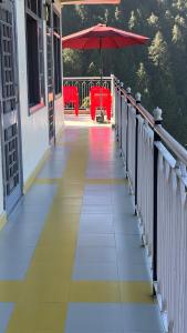 ein Gehweg mit Sonnenschirm und Stühlen auf einem Balkon in der Unterkunft FORTUNE HEIGHTS DALHOUSiE in Dalhousie