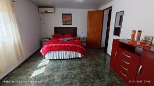 Schlafzimmer mit einem Bett mit einer roten Bettdecke in der Unterkunft Casa proxima a zona comercial in Rivera