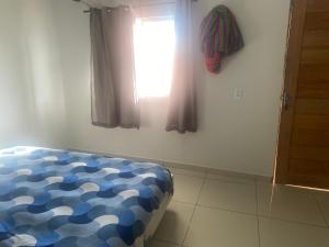 a bedroom with a bed with a blue and white comforter at Chalé Portal das Lagoas in Santo Amaro