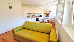 a living room with a yellow couch and a kitchen at -Parcheggio Privato-Riscaldamento Pavimento-WiFi- zona OSPEDALE-CENTRO "COZY PANoRAMA" in Trento
