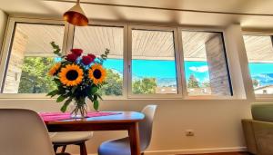a vase of flowers on a table in front of windows at -Parcheggio Privato-Riscaldamento Pavimento-WiFi- zona OSPEDALE-CENTRO "COZY PANoRAMA" in Trento