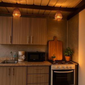 a kitchen with a sink and a stove and a microwave at Doa Blanca Cabin Mountain View in Utuado