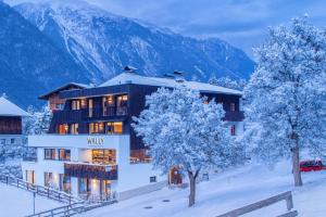a hotel in the snow with mountains in the background at Wally Berg-Appartements in Zams