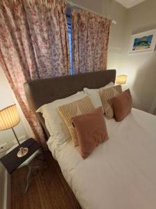 a bedroom with a bed with pillows and a window at 2 Courtyard Mews in Penzance