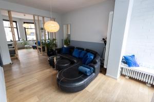 a living room with a black leather couch and blue pillows at Townhouse Tongeren Center 275m2, 10p - Featured in Designbook in Tongeren +113 photos