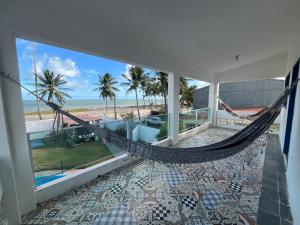 eine Hängematte in einem Zimmer mit Blick auf den Strand in der Unterkunft Casa vista Mar, pé na areia com piscina ! in Pitimbu